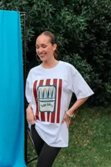 Remerón de algodón blanco con corte oversize y cuello redondo, que presenta un estampado frontal con diseño de una lata de sardinas sobre fondo de rayas.