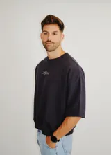 Buzo de cuello redondo y mangas tres cuartos, con corte holgado y diseño minimalista que incluye un pequeño estampado tipográfico en el pecho.