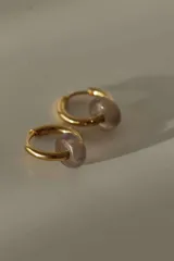 Par de aros tipo argolla dorados de acero quirúrgico, con una piedra natural de color gris translúcido colgando de cada uno.