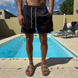 Short de baño rosado con estampado de siluetas negras, cintura elástica con cordón ajustable y logo estampado en la pierna.