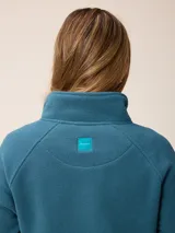 Sweater de polar con medio cierre frontal, cuello alto y mangas largas. Presenta un diseño liso en color azul petróleo con un pequeño logo bordado en el pecho.