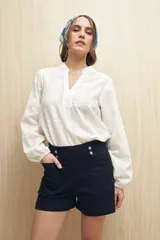 Short de jean color azul oscuro, de tiro alto con detalle de doble botón metálico en la cintura, bolsillos frontales y ruedo recto.