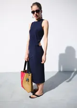 Vestido midi de punto fino color azul marino, de corte recto y sin mangas, con cuello redondo y espalda abierta asimétrica.