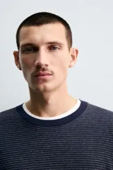Jersey de punto con diseño de rayas horizontales finas, cuello redondo y manga larga. Presenta un corte regular fit con terminaciones en rib en cuello, puños y ruedo.