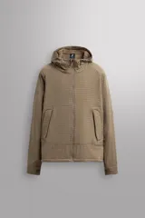 Chaqueta técnica color beige, corte regular, con capucha ajustable y cierre frontal de cremallera. Presenta bolsillos de vivo con solapa en la cadera y puños ajustables con tira adherente. El interior está forrado con tejido tipo forro polar.
