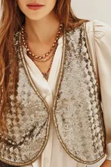Chaleco corto con diseño de lentejuelas brillantes en tono dorado y plateado. Presenta un corte clásico con bordes definidos y forro interior suave.