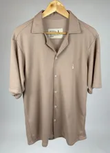 Camisa color beige de tejido texturizado con cuello solapa, cierre frontal con botones y manga corta con dobladillo.