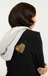 Blazer negro con capucha gris, solapas con muescas, cierre con botones y bolsillos con solapa en la parte delantera. Decorado con parches bordados de corazones, estrellas y otros motivos.