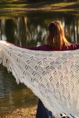 Bufandón triangular tejido en lana merino, con diseño calado y terminaciones con flecos largos en los extremos. Versátil para usar como bufanda o chal.