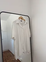 Vestido camisero blanco, holgado, con mangas 3/4 y puños elásticos.