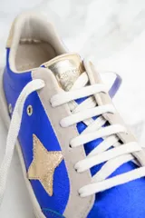 Zapatillas de cuero metalizado color azul con estrella dorada en el lateral, cordones blancos y detalles en color crema.