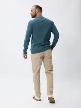 Sweater de tejido de punto fino en color gris, con cuello redondo, mangas largas y puños acanalados. Presenta un diseño liso con un pequeño detalle bordado en el pecho.