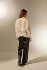 Blusa de poliéster color natural, con cuello en V, mangas largas con puños elásticos y detalle de frunces con cordón ajustable en el frente.