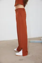 Pantalón de corte recto confeccionado en tela sastrera color ladrillo, con tajo lateral en la botamanga y bolsillos laterales.