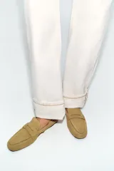 Mocasín de serraje color tostado, con copete subido, antifaz en la parte delantera y detalle fruncido en la parte trasera con tirador y aplique metálico.