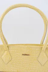 Cartera tipo baguette color negro con textura efecto cocodrilo, diseño alargado, doble asa de mano y cierre superior.