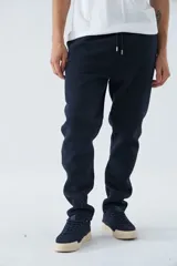 Pantalón deportivo de invierno, corte clásico con bolsillos laterales y cintura elástica con cordón ajustable. Presenta logo estampado y detalle en goma.