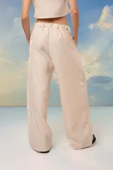 Pantalón beige de crepe de sastrería con lurex, tiro alto, corte sastrero, pinzas delanteras y pretina elastizada en la espalda.
