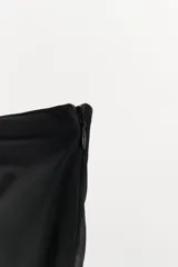 Top strapless negro con diseño asimétrico, confeccionado con una capa superior de tela opaca y una capa inferior de tejido semitransparente con caída irregular.