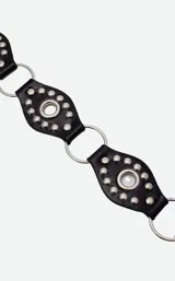 Cinto de cuero negro con diseño de piezas circulares unidas por argollas metálicas, decorado con tachas plateadas y tiras largas de cuero colgantes en el lateral.