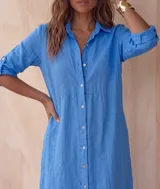 Vestido camisero midi blanco de lino, con cuello camisero, botonadura frontal completa con botones de nácar, mangas largas con tira para arremangar y abertura lateral en el bajo.