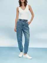 Pantalón jean de corte relaxed, con diseño cargo, cintura elástica con cordón ajustable y puños elastizados en los tobillos. Presenta bolsillos laterales en las piernas y bolsillos traseros.