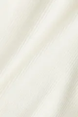 Top blanco de manga larga en tejido de punto acanalado, con escote Bardot (hombros descubiertos) y borde doblado.