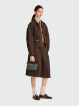 Cartera pouch tipo mini bolso de mano gris oscuro, con asa superior corta y solapa frontal con cierre de botón a presión.