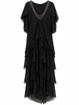 Vestido largo negro con escote en V ribeteado con pedrería, mangas cortas con volados y múltiples capas de volados en la falda con terminaciones deshilachadas.