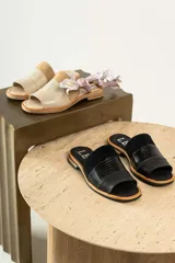Sandalias tipo chinela de cuero, con diseño de banda ancha que combina cuero liso, cuero texturizado y gamuza en tonos marrones. Presenta plantilla con logo grabado.