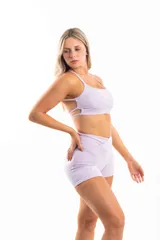 Conjunto deportivo negro compuesto por top con tirantes finos y logo blanco, y shorts de tiro alto con cintura cruzada y bolsillos laterales.