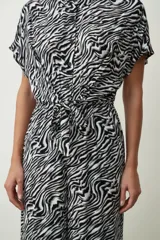 Mono largo negro de corte palazzo con camisa de mangas cortas con botones y lazo en la cintura.