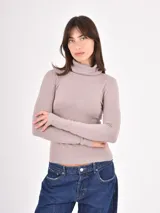 Polera de tejido de punto fino, con cuello alto doblado y mangas largas. Presenta un diseño ajustado al cuerpo con terminaciones acanaladas en puños y ruedo.