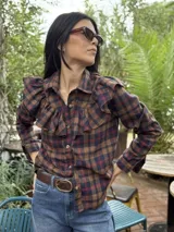 Camisa blanca de algodón con cuello clásico, cierre frontal de botones y detalle de volados en la parte delantera que se extienden hacia los hombros.