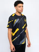 Remera de entrenamiento Fynar del Club Atlético Peñarol, color negro con estampado geométrico en amarillo y gris. Presenta cuello redondo, mangas cortas y el escudo del club en el pecho.