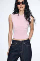 Chaleco de punto color blanco, estilo polo, sin mangas (manga sisa) y cuello solapa. La parte inferior termina en rib.