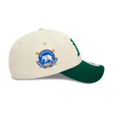 Gorro New Era 9FORTY ajustable, color crema con visera verde, logo del equipo Oakland Athletics bordado en verde y parche conmemorativo del campeonato de 1913 en el lateral.