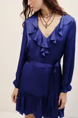 Vestido corto azul de viscosa con cuello en V, volados en el escote, mangas largas con puños fruncidos y falda con volado en el ruedo. Incluye un lazo para ajustar en la cintura.