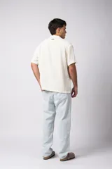 Camisa de manga corta con cuello cubano, confeccionada en lino entramado de textura natural. Presenta un corte relajado y cierre frontal con botones.