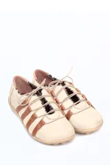 Zapato deportivo casual de cuero, con diseño de tiras laterales en contraste color marrón sobre base color crema. Presenta cierre con cordones y suela de goma con relieve.