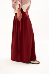 Pollera larga de corte recto con detalle de volado en la parte inferior, confeccionada en tela color bordó.