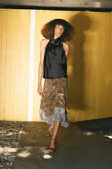Falda midi de tiro alto con bajo asimétrico y cierre frontal cruzado con botón. Presenta un diseño que combina estampado de lunares y animal print.