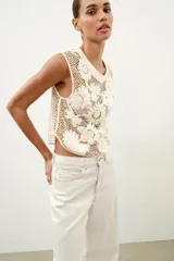 Top de crochet color crudo, sin mangas, con cuello redondo y detalle de aplicaciones de flores en relieve.