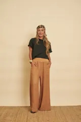 Pantalón de lino tostado, de corte amplio y evasé, con cintura estilo puño y bolsillos laterales.