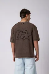 Remera de algodón gris con efecto acid wash, corte regular, mangas cortas y cuello redondo. Cuenta con un pequeño bordado tono sobre tono en el pecho y una etiqueta lateral distintiva de la marca en el ruedo.