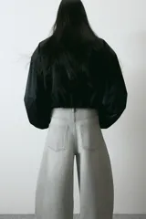 Pantalón de jean color gris claro, de tiro alto y diseño baggy con corte holgado en la cadera y piernas anchas estilo balloon.
