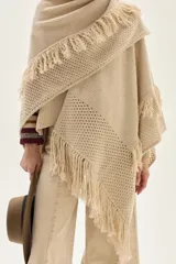 Ruana tejida en lana de cordero con diseño de sectores calados y terminación con flecos en los bordes.