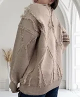Sweater beige de punto con cuello redondo y diseño con rombos y flecos.