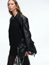 Blazer de ecocuero negro con silueta estructurada, solapas clásicas y cierre frontal mediante botones.