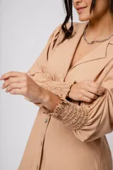 Vestido corto color tostado, con cuello solapa, abotonado al frente y mangas 3/4 con puños fruncidos.